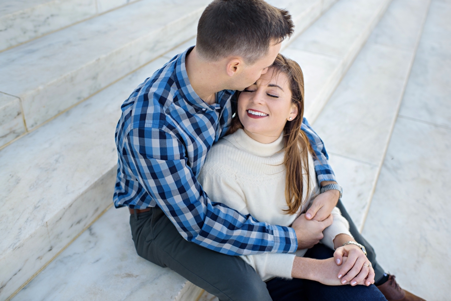 A man kisses his fiance on the marble steps of the lincoln memorial.